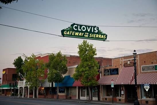Clovis Gateway to Sierras sign over historic downtown street with brick buildings and storefronts